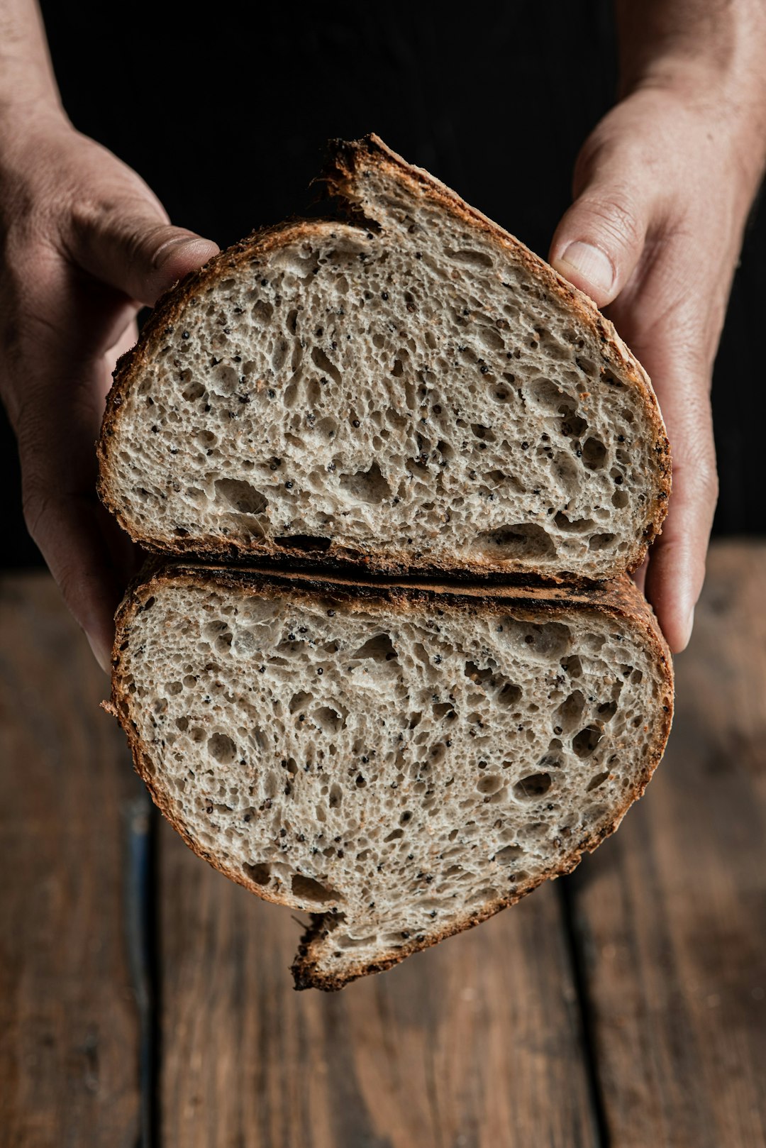 hands-holding-a-freshly-baked-loaf-of-sourdough-bread-smhplkxzja8