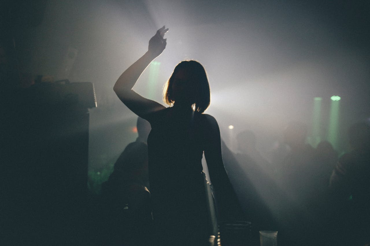 A woman silhouetted against lights, enjoying a night out at a lively club.